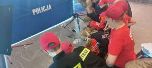 dzieci , w tle napis policja, porozrzucane przedmioty.